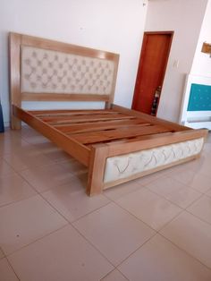 a large bed sitting on top of a white tiled floor next to a wooden headboard