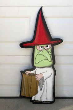 an image of a green man with a red hat sitting in front of a garage door