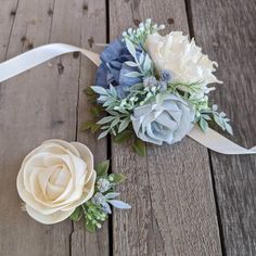 two flower bouquets sitting on top of a wooden table next to ribbons and ribbon