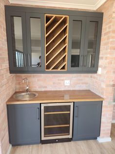 an empty kitchen with grey cabinets and a sink in the middle, next to a brick wall