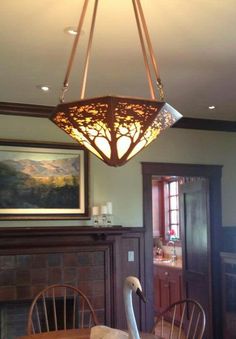 a chandelier hanging from the ceiling over a dining room table with two swans on it