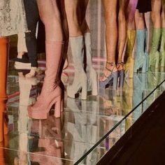 several women's legs in high heeled boots standing on the floor with their reflection