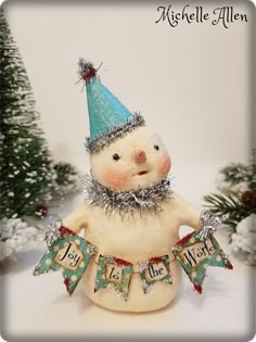 a snowman figurine with a blue hat and banner around it's neck