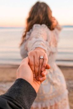 a man and woman holding hands on the beach