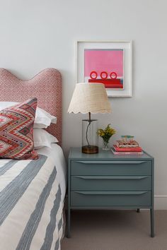 a bedroom with a bed, nightstand and painting on the wall