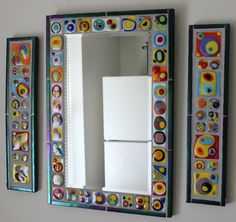 two colorful mirrors mounted to the side of a wall