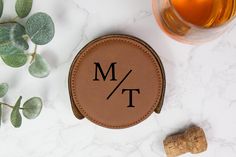 a leather coaster sitting next to a bottle of wine and a cork with the word mt on it