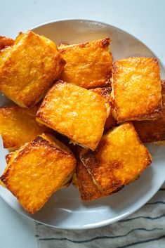 a white plate topped with tofu pieces on top of a table