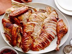 a white plate topped with sliced chicken next to bowls of cranberry sauce