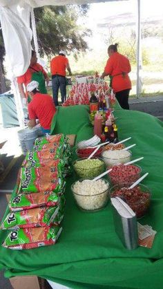 several people standing around a green table covered in food and candy bar wrappers