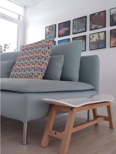 a blue couch with pillows on it in front of a wall full of framed pictures