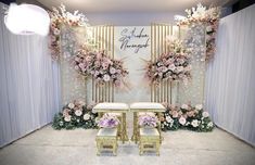 two chairs sitting next to each other in front of a wall with flowers on it