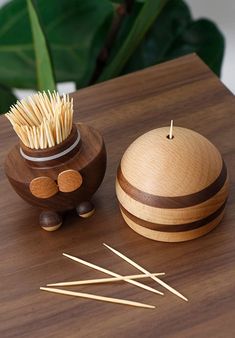 a wooden container with toothpicks in it on a table next to a potted plant