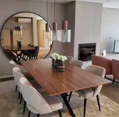 a dining room table with chairs and a large round mirror