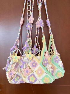 three purses hanging from the wall with beads and flowers attached to them, all decorated in pastel colors