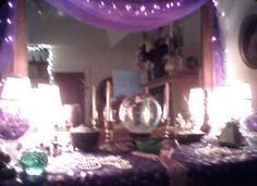 a table topped with lots of purple and white decor next to a mirror covered in lights