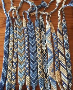 several pieces of blue and white knitted fabric hanging on a wooden table next to yarn balls