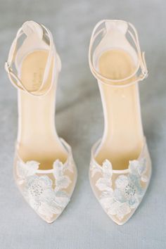 a pair of white shoes with flowers on the toes and heels are sitting next to each other