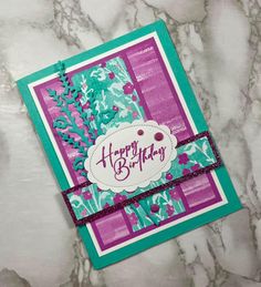 a happy birthday card on a marble surface with pink and green flowers in the background