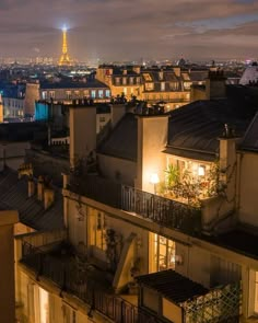 the eiffel tower is lit up in the distance behind some buildings at night