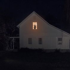 a white house at night with the lights on and windows lit up in the dark