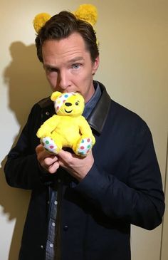 a man holding a yellow teddy bear in front of his face