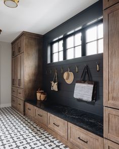 a black and white tiled floor in a room with wooden cabinets, hanging utensils and other items