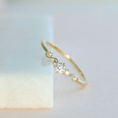 a gold ring with three small diamonds on the top and one smaller diamond in the middle