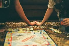 two people playing a board game on the floor with their hands touching each other's fingers