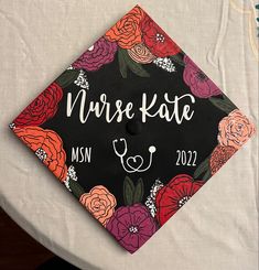 a graduation cap with flowers on it sitting on top of a white cloth covered table