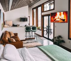 a living room filled with furniture and a fire place in the wall next to a kitchen