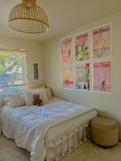 a bedroom with posters on the wall and a white bed in front of a window