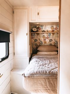 a small bedroom with a bed in it and shelves above the bed that are built into the wall