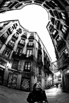 black and white photograph of a woman looking up at the sky through an arch in a building