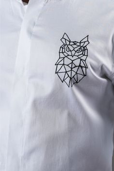 a man wearing a white shirt with an owl embroidered on the chest and black outline