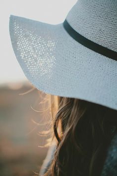 a close up of a person wearing a white hat with the sun shining on them