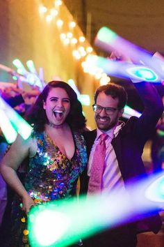 two people standing next to each other at a party with lights on the ceiling and in front of them