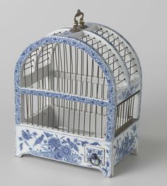 a blue and white birdcage with two birds on it's top shelf