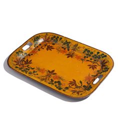 an orange and yellow serving tray with flowers on the bottom, sitting on a white surface