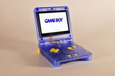 a blue gameboy sitting on top of a plastic case next to a yellow object