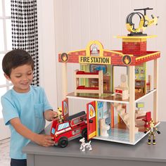 a young boy playing with a fire station playset