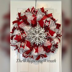 a red and white snowflake wreath hanging on a door with the words, the whispering