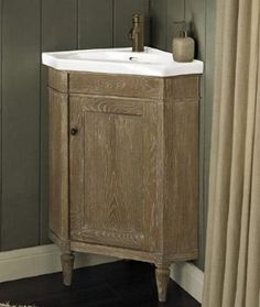 a bathroom vanity with a white sink and wooden cabinet in front of a green wall