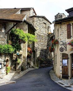 an old european street with stone buildings and flowers on the windows, along with cobblestone streets