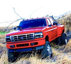 a red truck is parked in the tall grass