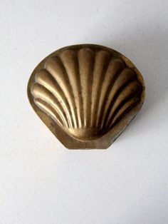 a gold shell shaped object on a white surface