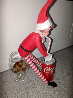 an elf is on top of a coke can and has his legs in the air