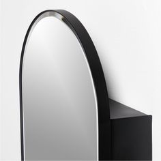 a black and silver mirror mounted to the side of a wall next to a shelf