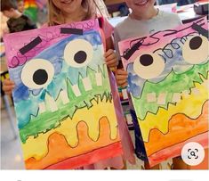 two children holding up paintings with faces painted on them