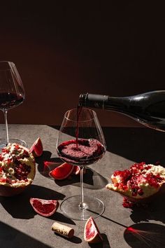 a table topped with glasses of wine next to sliced fruit